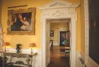 A doorway from the Drawing Room showing several oil paintings at Kirtlington Park